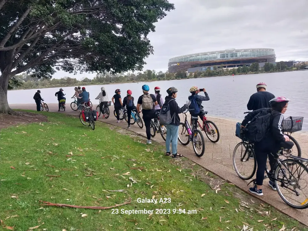 Cyclists from the church riding beside the river near Optus Stadium